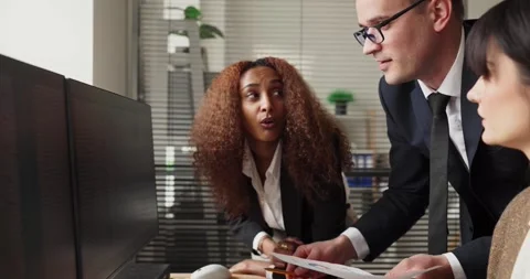Business analysts reviewing financial data on dual monitors for strategy meeting Stock Footage 340063642