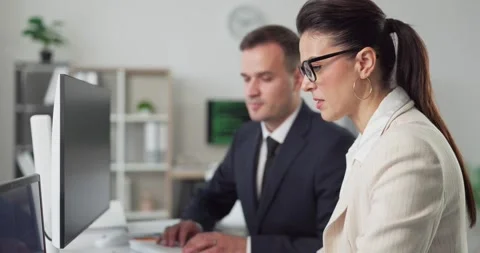 Business analysts working at computers in office, man and woman reviewing data Stock Footage 328278882