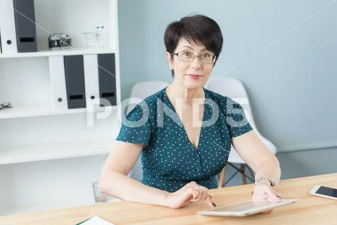Business and people concept - middle aged confident woman is working with tablet Stock Photos