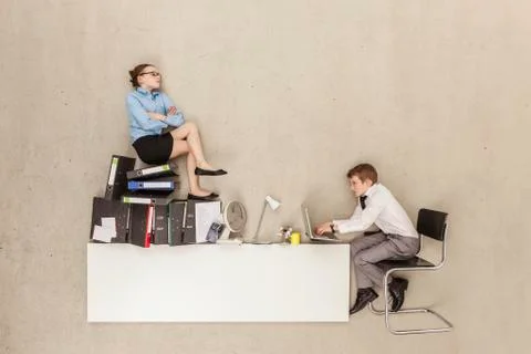 Business boy using laptop while girl sitting on stack of files 스톡 사진