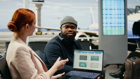 Business CEO and assistant evaluating company data and KPIs in airport lounge Stock Footage 339643160