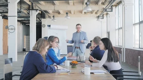 A business coach conducts a presentation using a flipchart and talks with Stock Footage 111648806