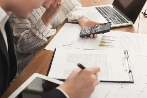 Business colleagues checking documents and using calculator Stock Photos