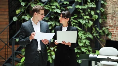Business Colleagues Discuss a Project Using Documents and a Laptop in a Modern Stock-Footage 311560943