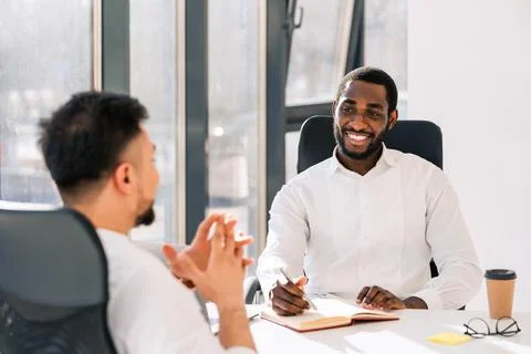 Business colleagues talking while sitting at the table in the office Stock Photos