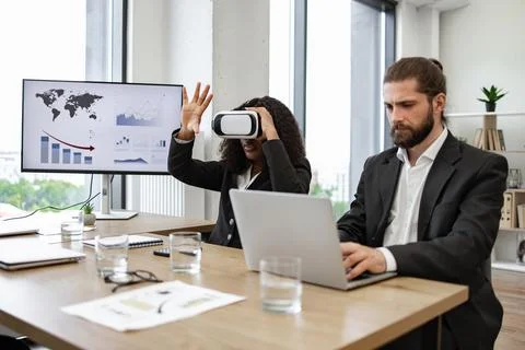 Business colleagues using virtual reality and working on laptops Stock Photos