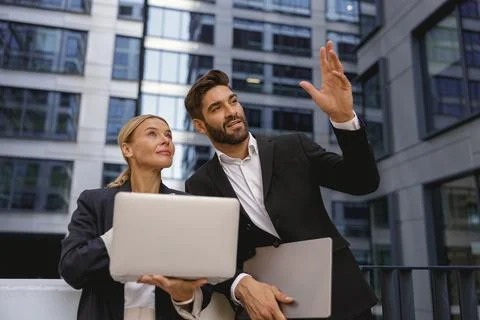 Business colleagues working on project while sitting outdoors on skyscrapers Foto stock