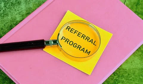 Business concept. Text REFERRAL PROGRAM through a magnifying glass on a yello Stock Photos