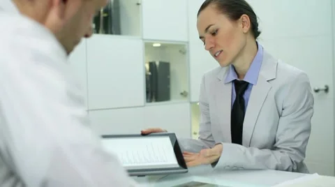 Business consultant explaining something on digital tablet to male client Stock Footage 10786447