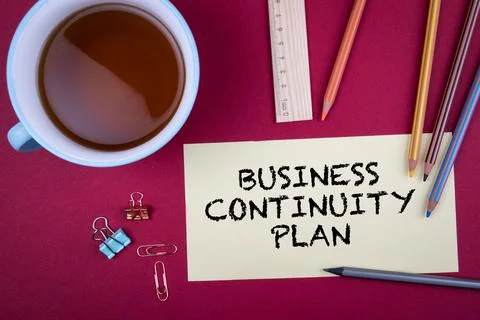 BUSINESS CONTINUITY PLAN. Note sheet and office supplies on a red background Stock Photos