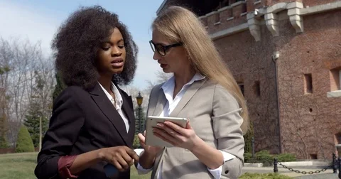 Business conversation between two young multi-cultural businesswomen in suits Stock Footage 84453817