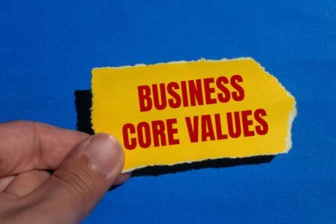 Business core values message written on ripped torn yellow paper with blue ba Stock Photos