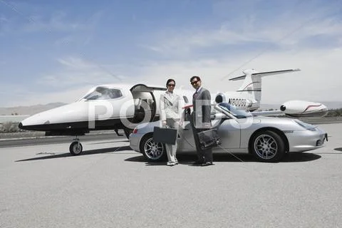 Business Couple Standing In Front Of Convertible And Private Jet Stock Photos