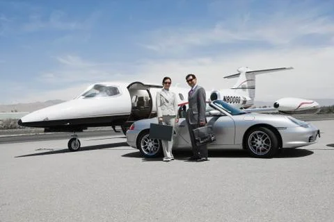 Business Couple Standing In Front Of Convertible And Private Jet Stock Photos