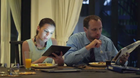 Business couple with tablet computer and newspaper eating dinner at home HD Stock Footage 42312510