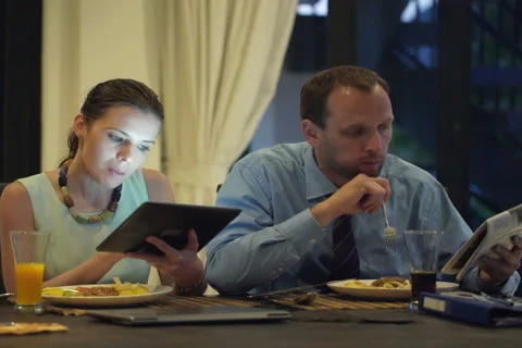 Business couple with tablet computer and newspaper eating dinner at home NTSC Stock Footage 42312521