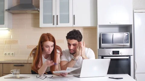Business couple with tablet computer and bills in kitchen at home. Stock Footage 82695640