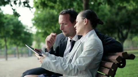 Business couple with tablet computer in the park, dolly shot HD Stock Footage 11150268