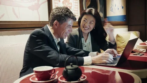 Business discussion between two professionals at a cafe with tea and laptop Stock-Footage 304540619