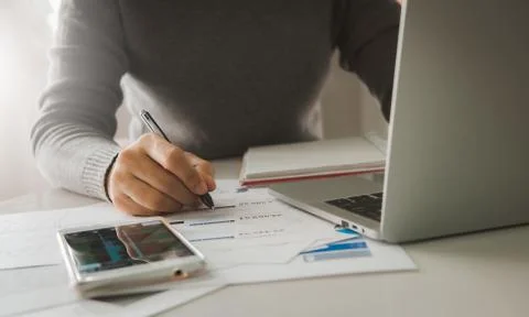 Business documents on table with smart phone and laptop computer and woman wo Stock-Fotos