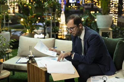 Business executive sorting folder with financial report after hours Фото