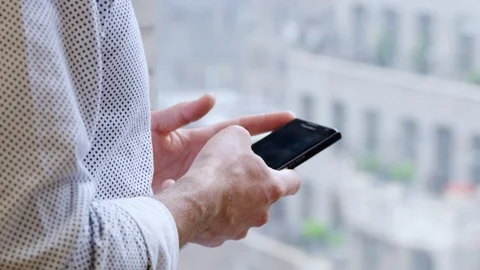 Business executive typing a message on his smartphone near the window Stock Footage 93515902