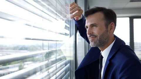 Business executive walking over to lean against office window and looking out Stock Footage 114813014