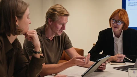Business Executives Analyzing Data on Tablet in Office Meeting Stock Footage 347653451