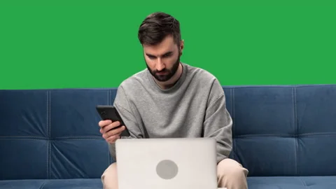 Business freelancer man working remotely use smartphone laptop sitting couch Stock Footage 229878193