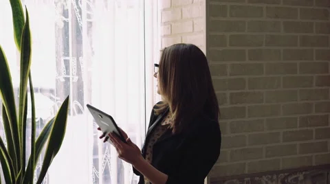 Business girl using a tablet on a window and sunset background. 4k Vídeo Stock 62449134
