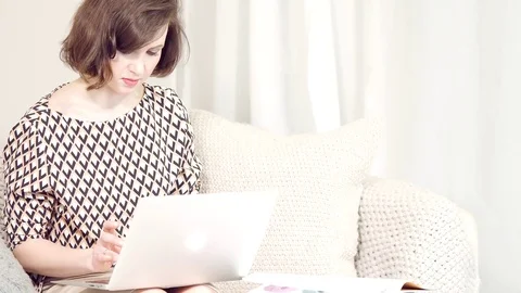 Business girl works at the computer in the Internet . sitting on the couch in Stock Footage