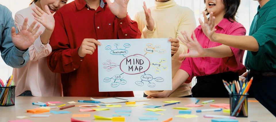 Business group presents strategy using a mind map while waving hand. Variegated. Stock Photos