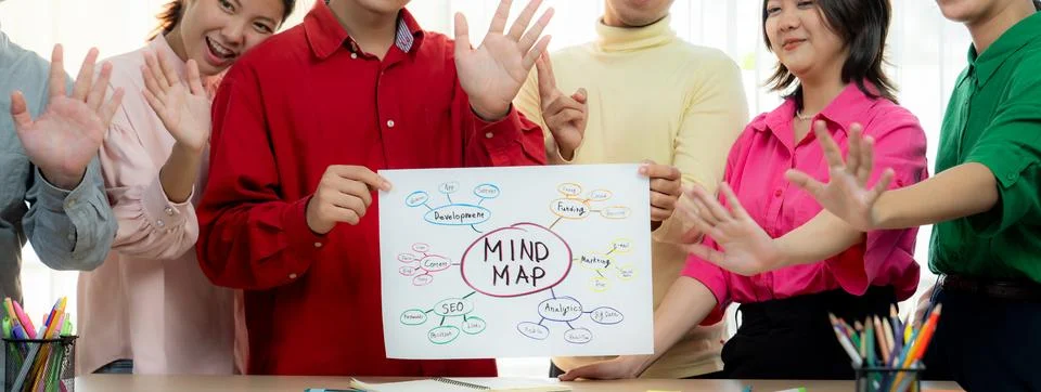 Business group presents strategy using a mind map while waving hand. Variegated. Stock Photos