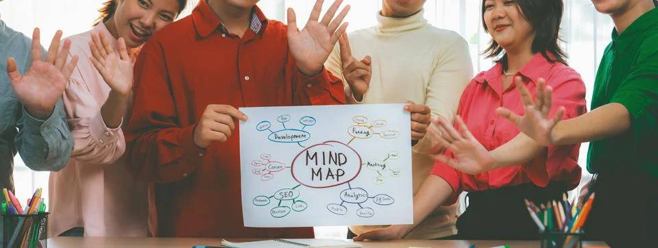 Business group presents strategy using a mind map while waving hand. Variegated. Stock Photos