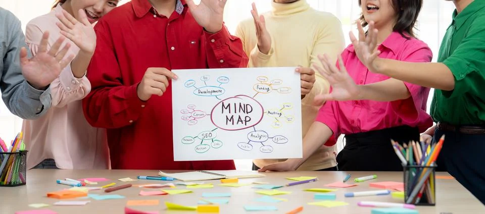 Business group presents strategy using a mind map while waving hand. Variegated. Stock Photos