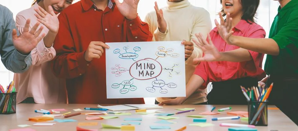 Business group presents strategy using a mind map while waving hand. Variegated. Stock Photos