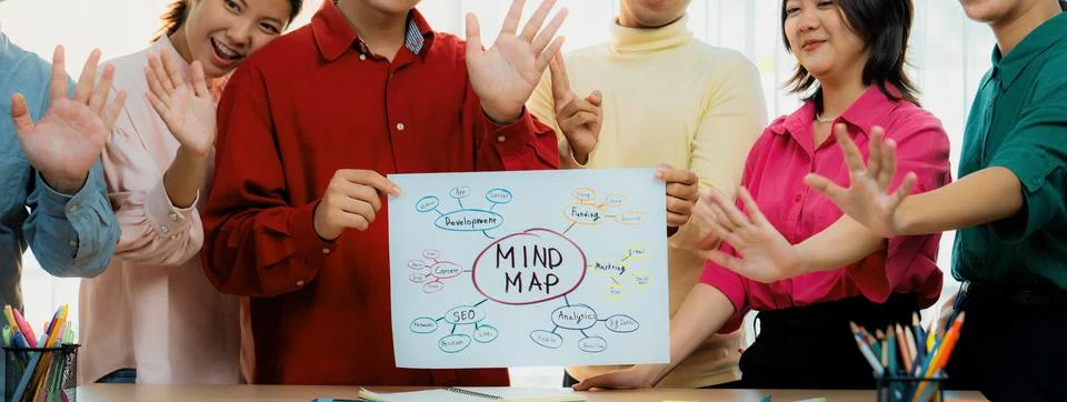 Business group presents strategy using a mind map while waving hand. Variegated. Stock Photos