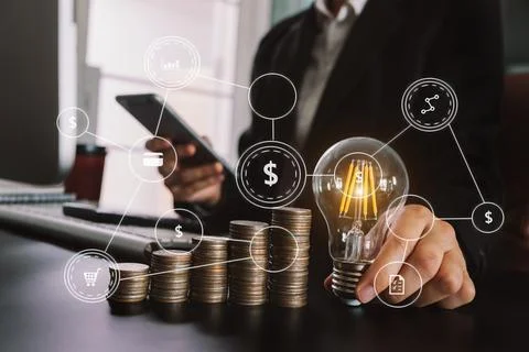 Business hand holding lightbulb with using laptop computer and money stack .. Stock Photos