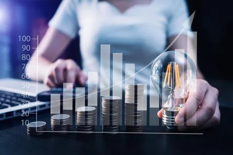 Business hand holding lightbulb with using laptop computer and money stack .. Stock Photos