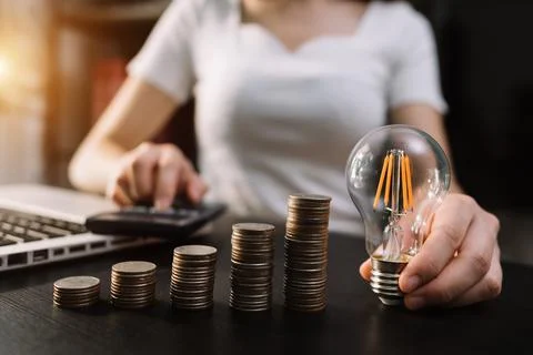 Business hand holding lightbulb with using laptop computer and money stack .. Stock Photos