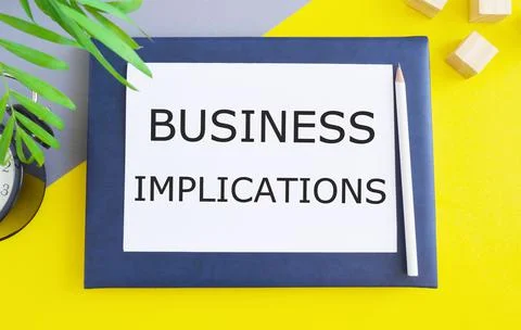 Business implications text memo written on a white paper above Notebook with Stock Photos
