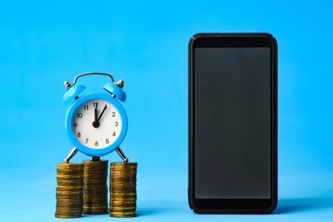 Business items - watch, stack of coins and phone on a blue background Stock-Fotos