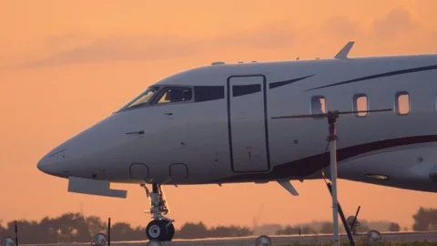 Business jet taxiing on a taxiway before taking off at sunset Stock Footage