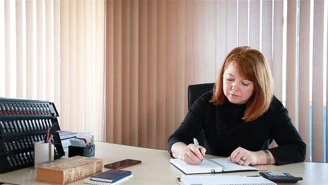 Business lady makes notes and talks on the phone in her office Stock Footage 100441312