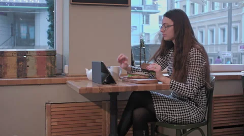 Business lady using tablet while eating sandwich in the cafe Stock Footage 60998636