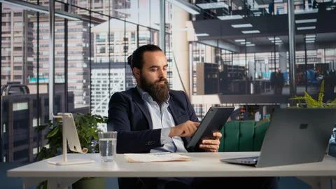 Business leader fact-checking documents with company data and KPIs on tablet Stock Photos