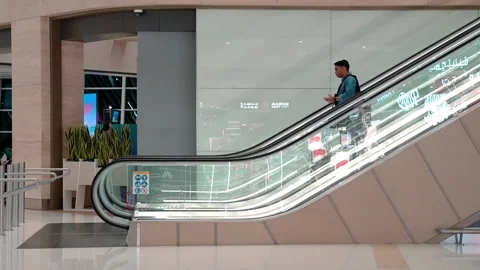 Business-looking man goes down the escalator at the airport Video stock 224538943