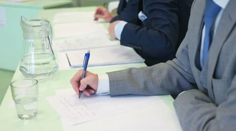 Business like looking student writing down notes and drinking after placing down Stock Footage 56909434