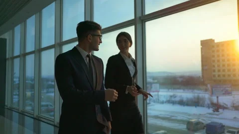 The business man and a woman walking along the window. slow motion Stock Footage