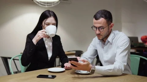 Business man and wonan drinking coffee discussing and looking at smartphone Stock Footage 77146682